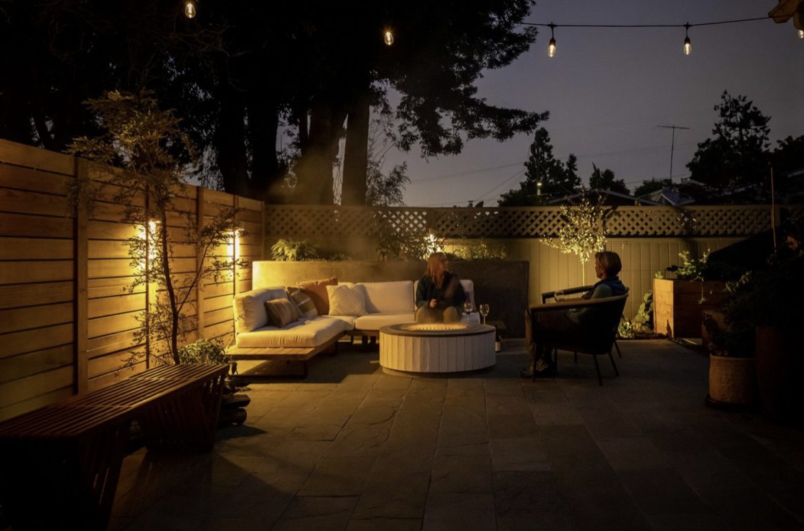 Bungalow backyard with fire pit, seating, planting, and evening lighting